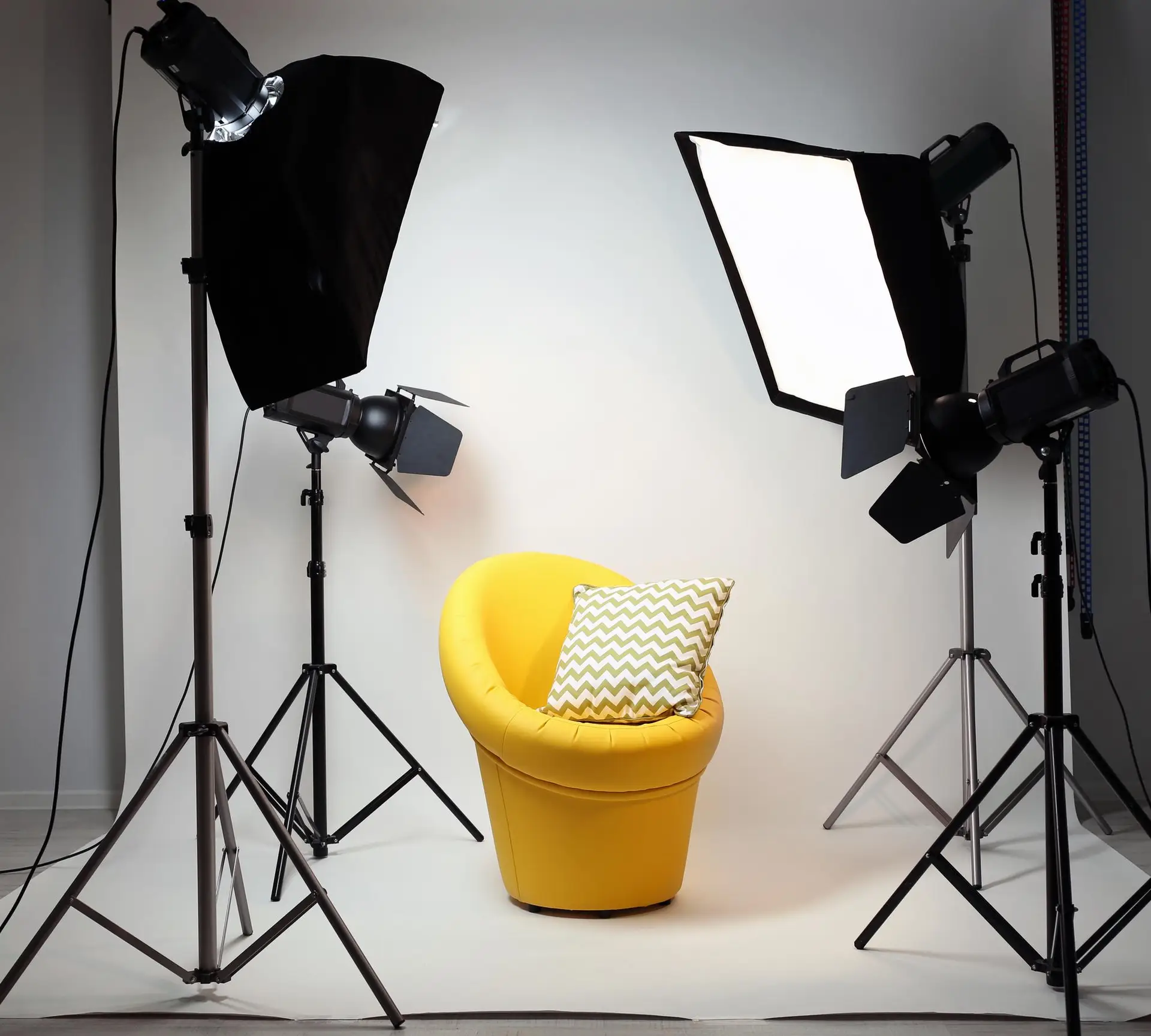 Professional photography studio with softbox lights and yellow chair setup for portrait shoots