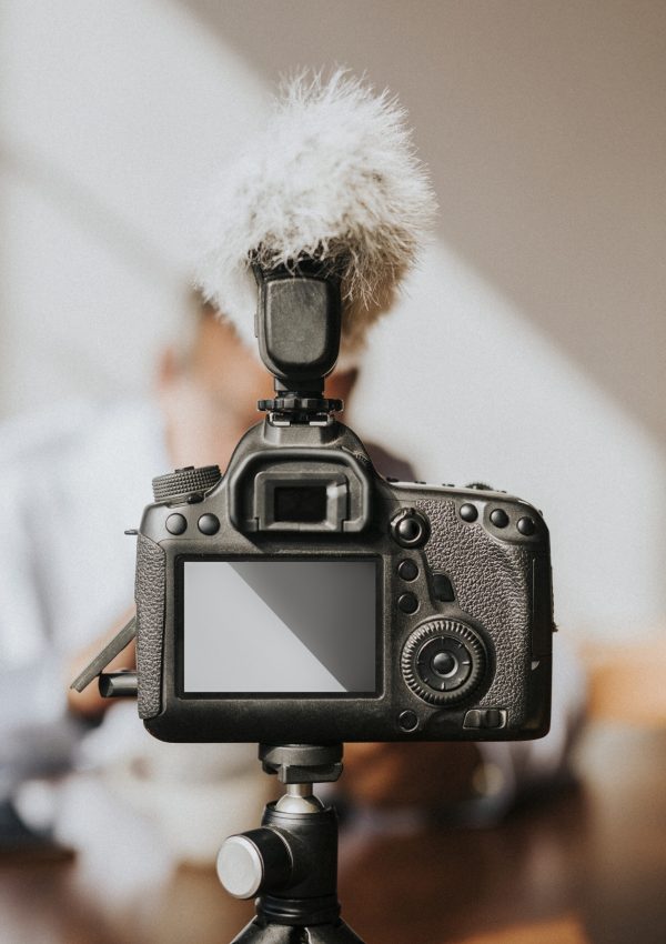 Professional DSLR camera with external microphone mounted on tripod for video production