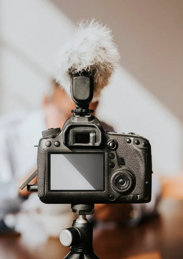 Professional DSLR camera with external microphone mounted on tripod for video production